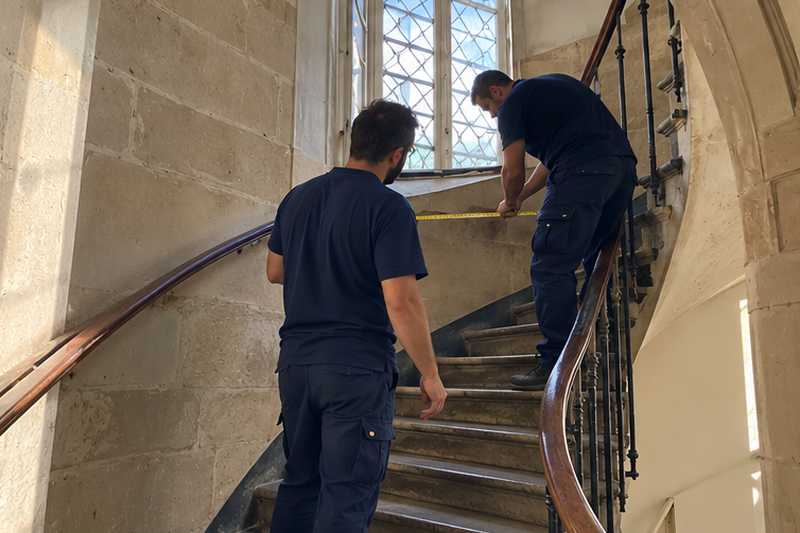 Deux équipiers mesurant la largeur d'un escalier à quart tournant